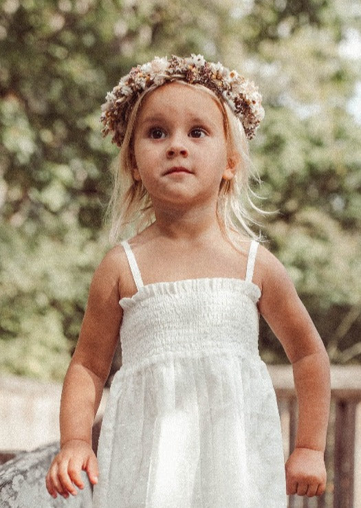 girl with flowercrown wearing a white smocked top with straps